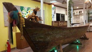 A large wooden boat model displayed indoors with a 'Room Reservation' sign nearby. - Sea Falcon Hotel (Sattahip)