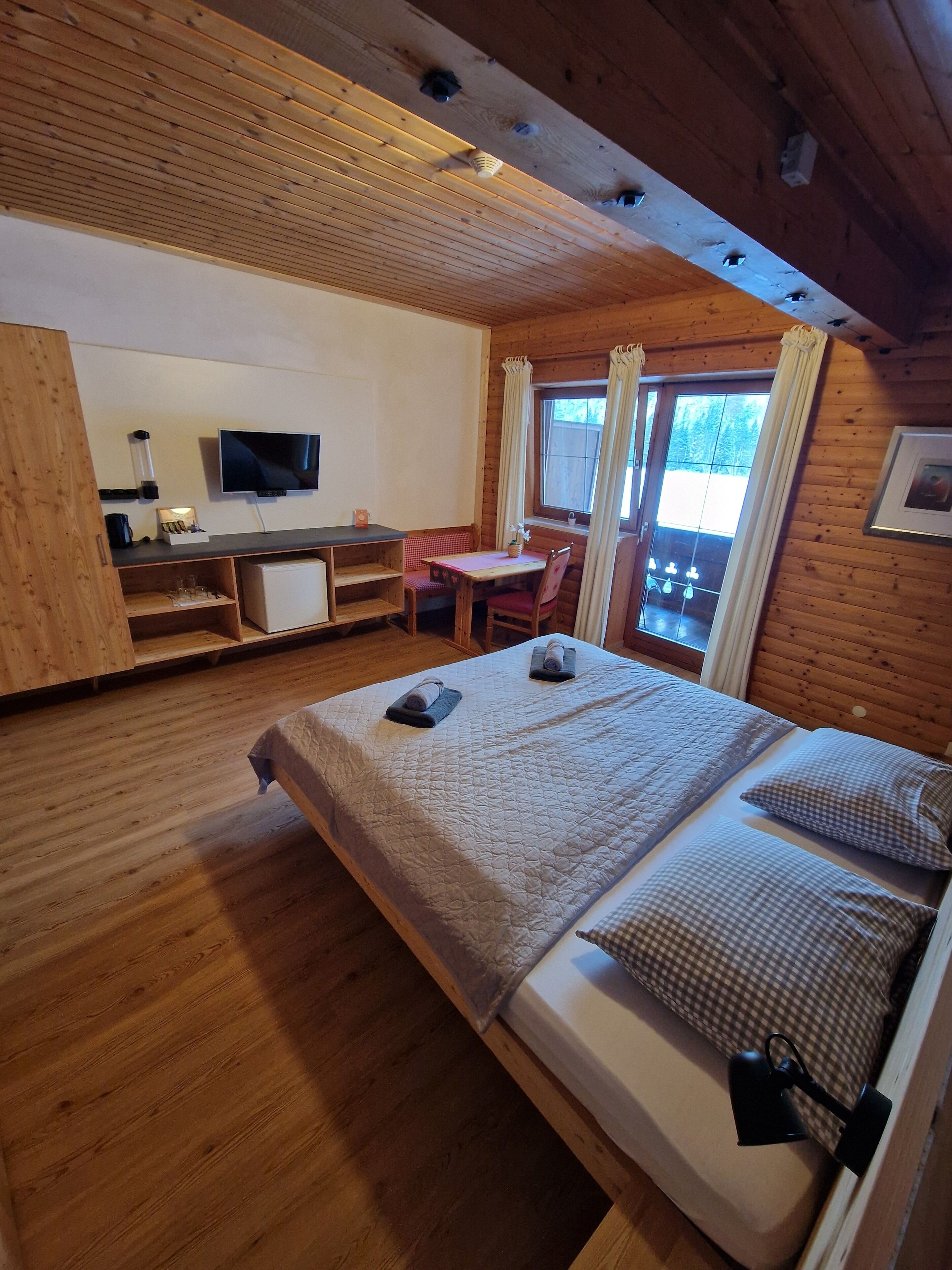 Een gezellig houten kamer met een bed, een bureau, een stoel en een televisie.