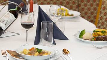 Una mesa de comedor con platos de comida, copas de vino y una botella.