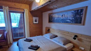 Een houten slaapkamer met een groot bed, een foto aan de muur en een raam met gordijnen.