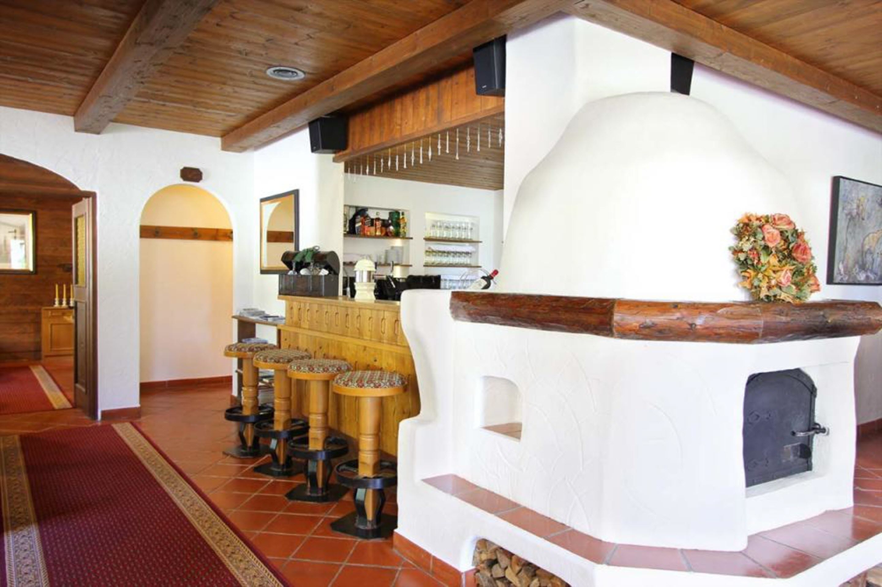 A rustic interior with a stone oven, wooden stools, and a bar area.