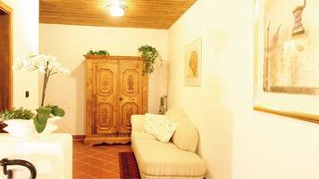 A room with a wooden cabinet, a sofa, a white table with a plant, and a framed picture on the wall.