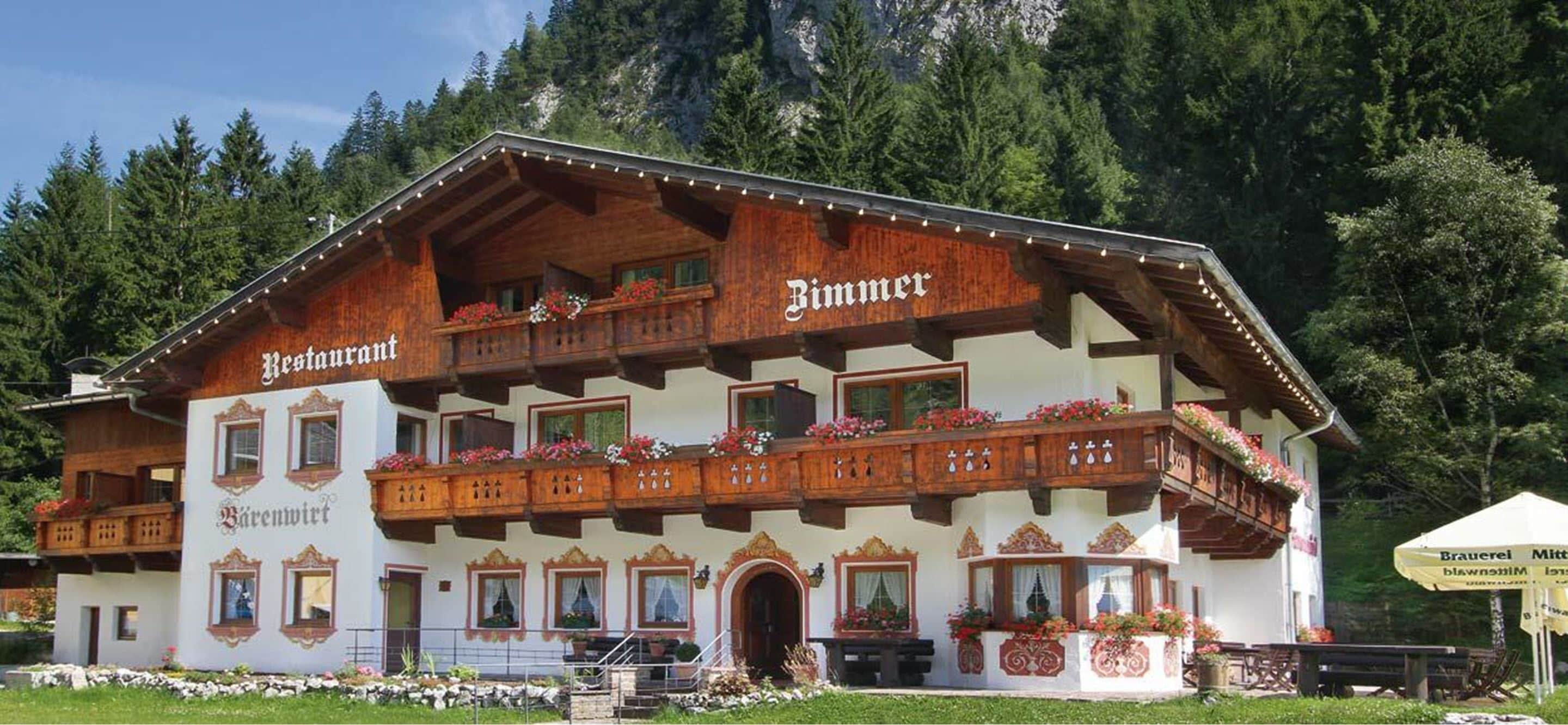 Ein traditionelles Holzhaus mit Balkonen, mit der Aufschrift "Restaurant Bärenwirt" und "Bimmer".