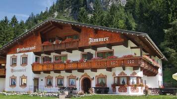 Ein traditionelles Holzhaus mit Balkonen, mit der Aufschrift "Restaurant Bärenwirt" und "Bimmer".