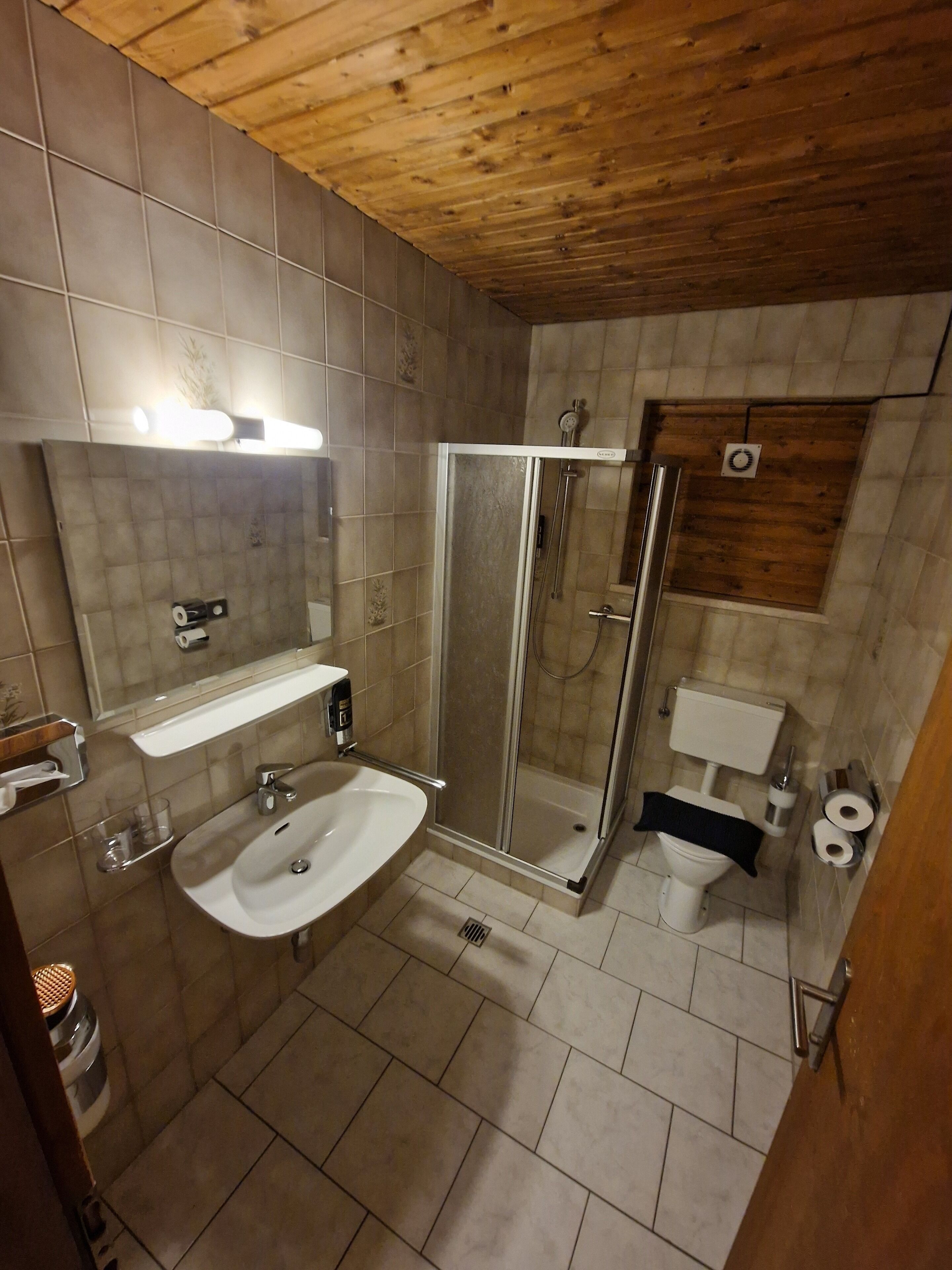 A bathroom with a shower, toilet, sink, and a mirror.