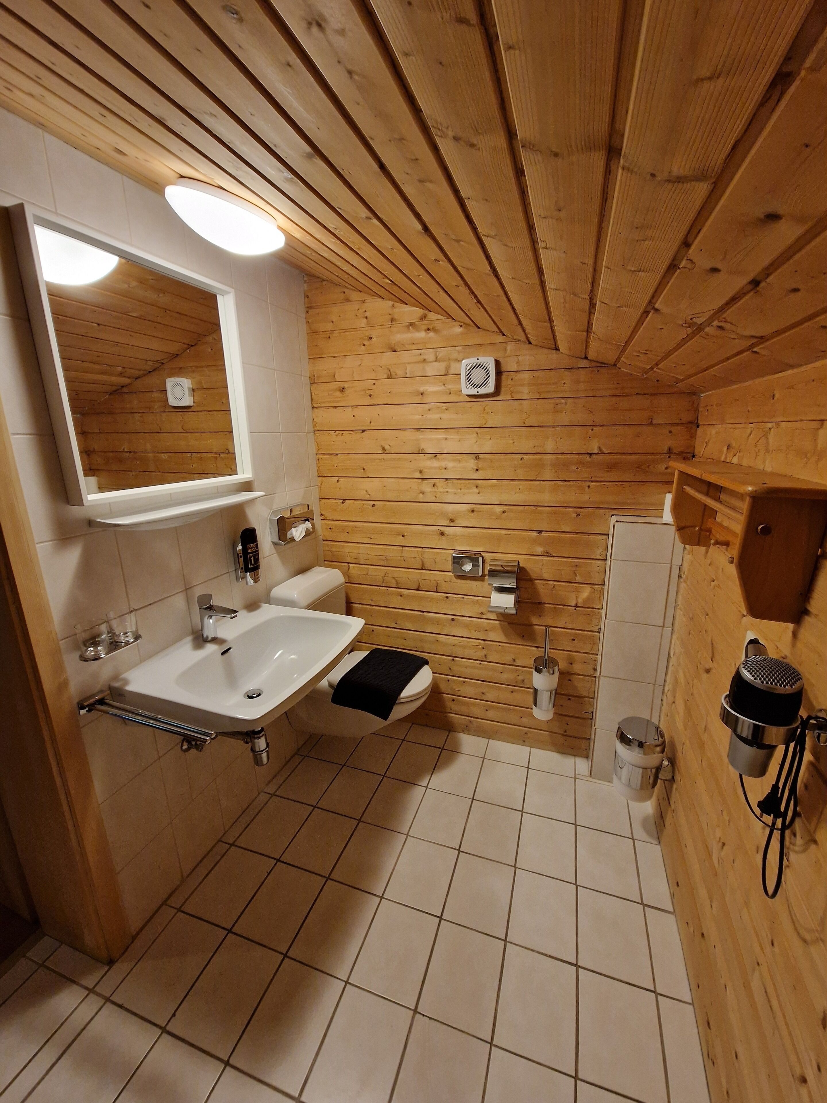 A wooden-paneled bathroom with a sink, toilet, and mirror.