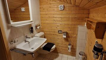 A wooden-paneled bathroom with a sink, toilet, and mirror.