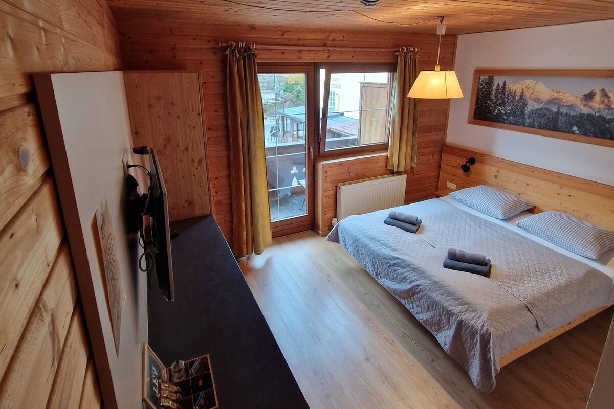Une chambre dans un chalet en bois, avec un lit, un bureau et une fenêtre.