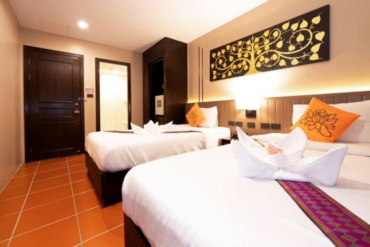 A hotel room with two beds, a large decorative wall piece, and a tiled floor.