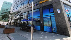A multi-story hotel with a prominent 'Grand Open' sign, outdoor seating area, and a modern glass facade. - Inter City Seoul (Seoul)