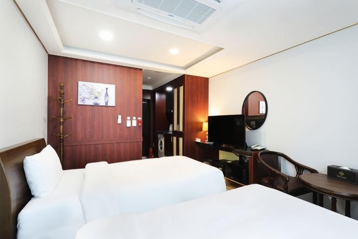 A hotel room with a bed, a desk, a chair, a television, and a mirror.