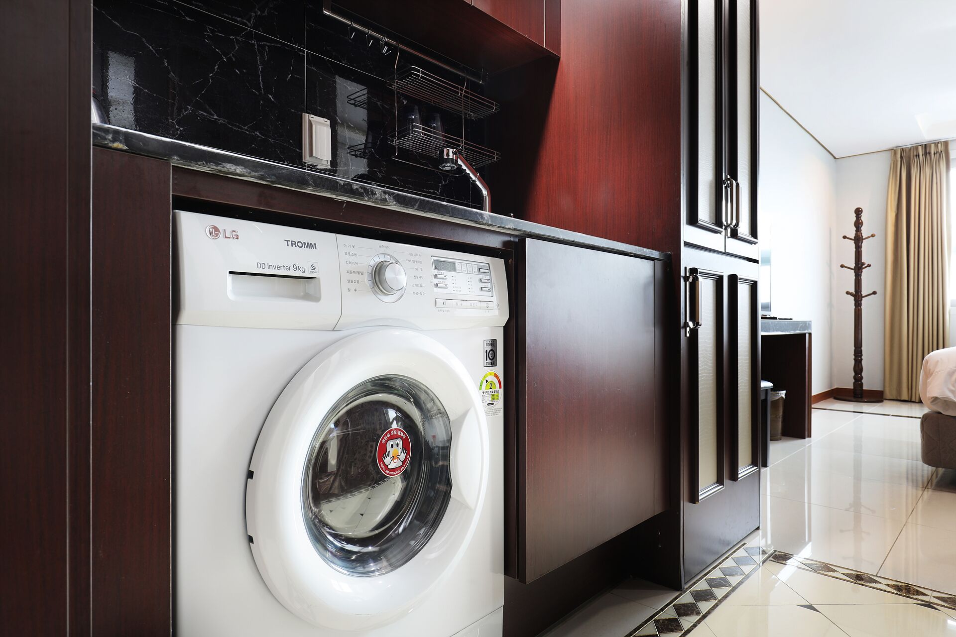 A compact laundry room with a front-loading washing machine, a built-in dryer, and a small countertop with a microwave.