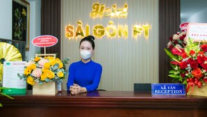 Een receptiebalie met een bordje met de tekst 'HEAD SAIGON PT' en een bordje 'LE TÂN RECEPTION'. Er staan bloemstukken op de balie.