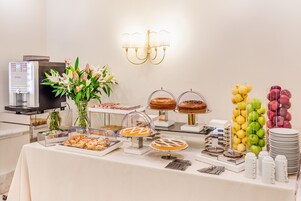 A buffet table with various food items and a coffee machine.