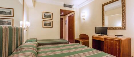 Quarto de hotel com duas camas, uma escrivaninha, televisão e quadros na parede.