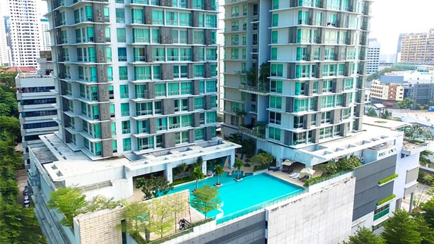 Un edifici residencial alt amb nombroses galeries i una piscina al terrat.