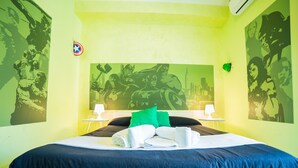 A hotel room with a bed, green walls, and superhero-themed artwork. - Movie Home B&B (Rome)