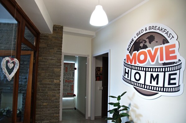 Un pasillo con un letrero en la pared que dice "MOVIE HOME" y menciona "HOME - BED & BREAKFAST".