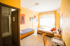 A room with two beds, a desk with a chair, a TV, and a shower area. - Movie Home B&B (Rome)