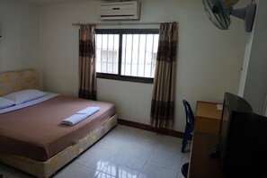 A hotel room with a bed, a window with curtains, an air conditioning unit, a desk with a television, and a chair. - Mixok Guesthouse (Vientiane)