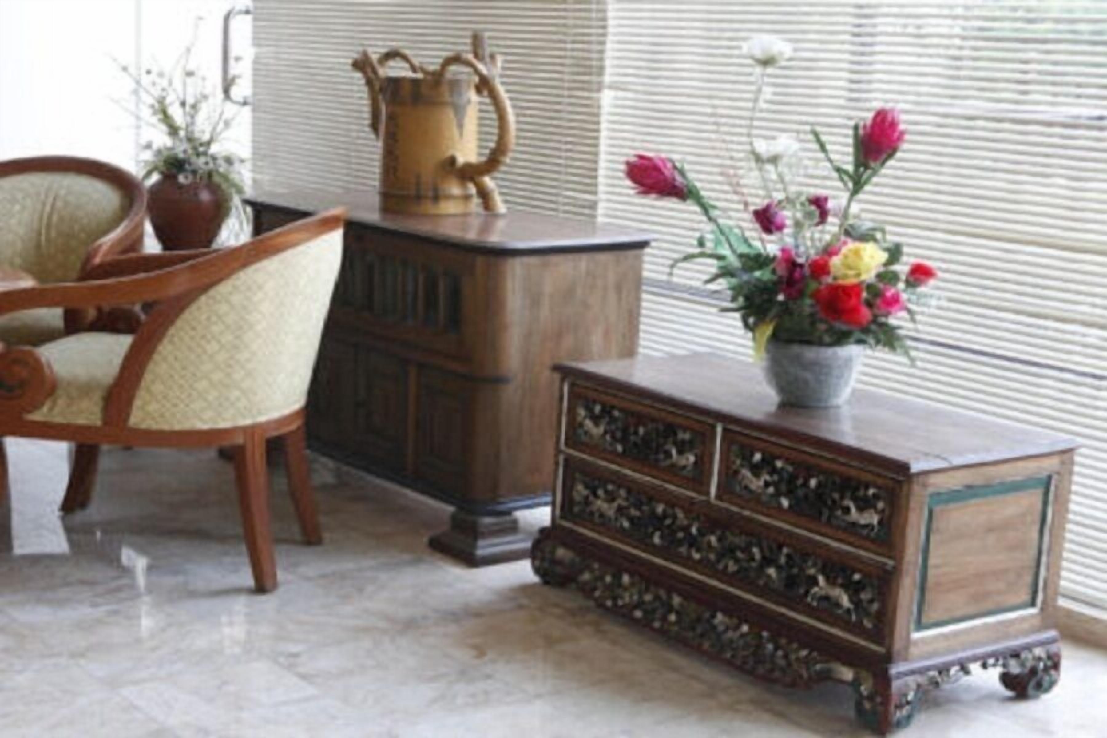 Une pièce avec un meuble en bois, une chaise et un vase rempli de fleurs.