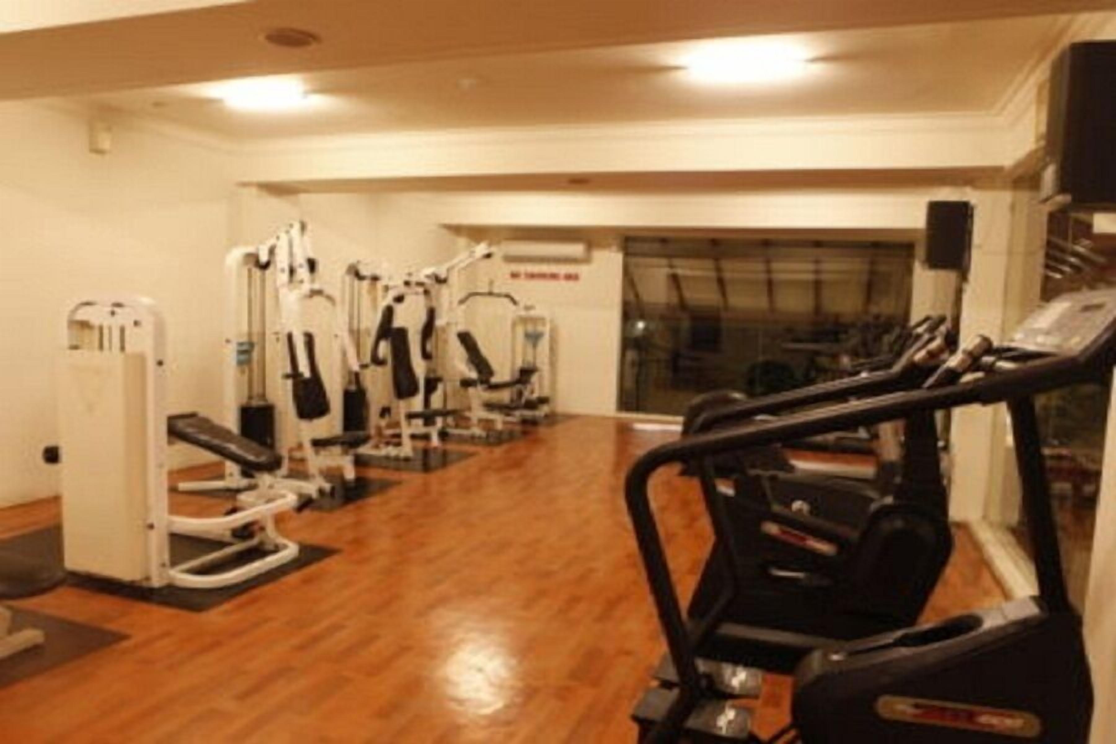 A gym with cardio machines, weight machines, and a mirrored wall.