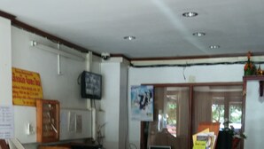 Un área de recepción con un mostrador de madera, un televisor montado en la pared y un cartel con texto.