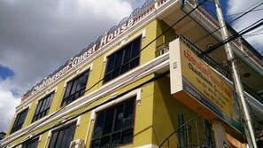 Un edificio a più piani con facciata gialla, ampie finestre e un balcone con ringhiere.