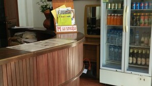 Una zona de recepción con mostrador de madera, un refrigerador de Pepsi y un reloj en la pared.