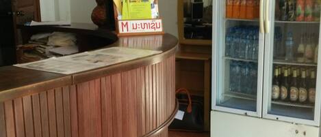 A reception area with a wooden counter, a Pepsi refrigerator, and a clock on the wall.