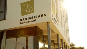 Vue dégagée sur la façade et l’enseigne du bâtiment, prise de l’extérieur du Maximilians Boutique-Hotel.