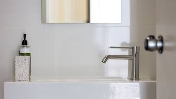A bathroom with a white sink, a modern faucet, and a soap dispenser on the counter.