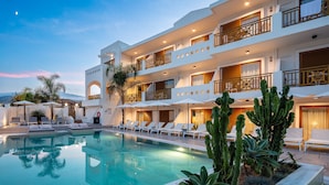 A modern hotel with a pool, multiple balconies, and outdoor seating areas.
