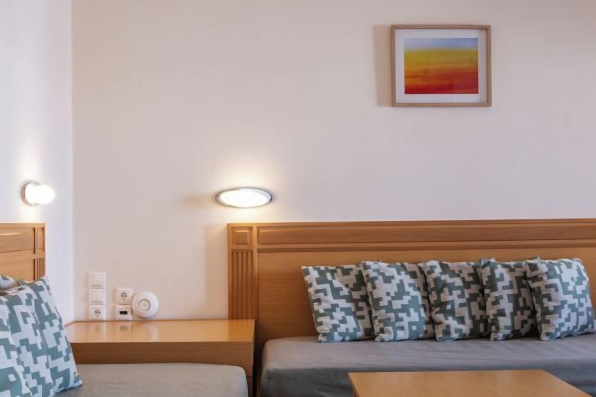 A hotel room with two beds, a wooden headboard, and a wall-mounted painting.
