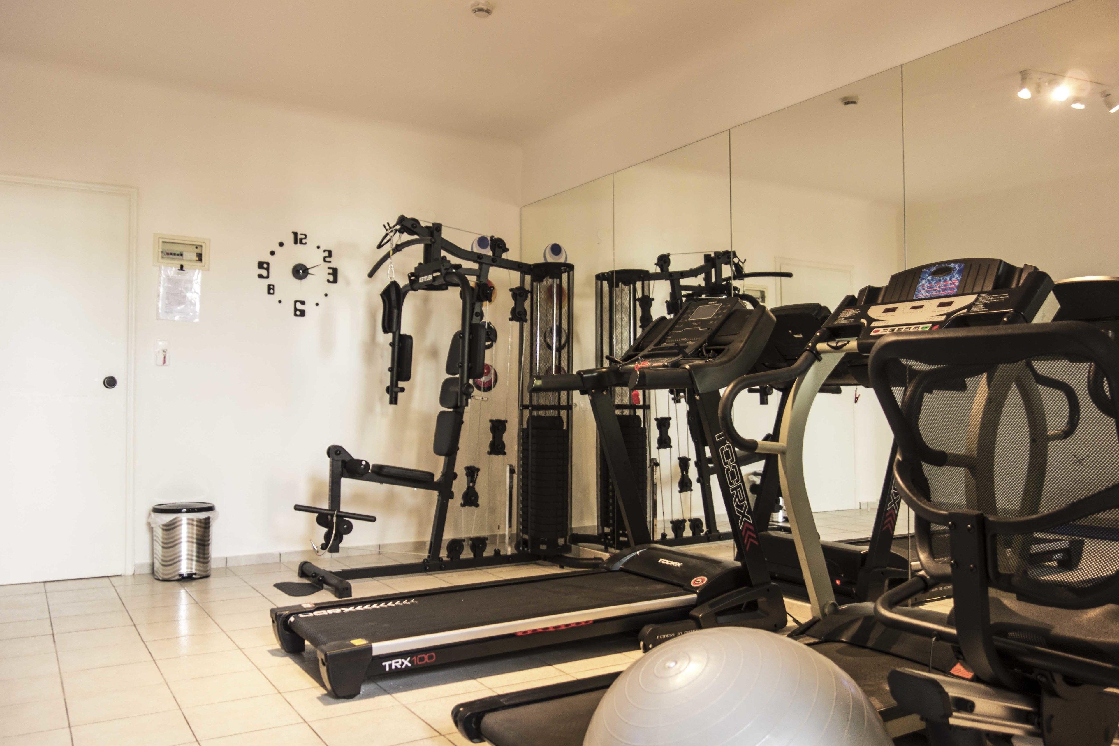 A home gym with a treadmill, elliptical, and weight machines.