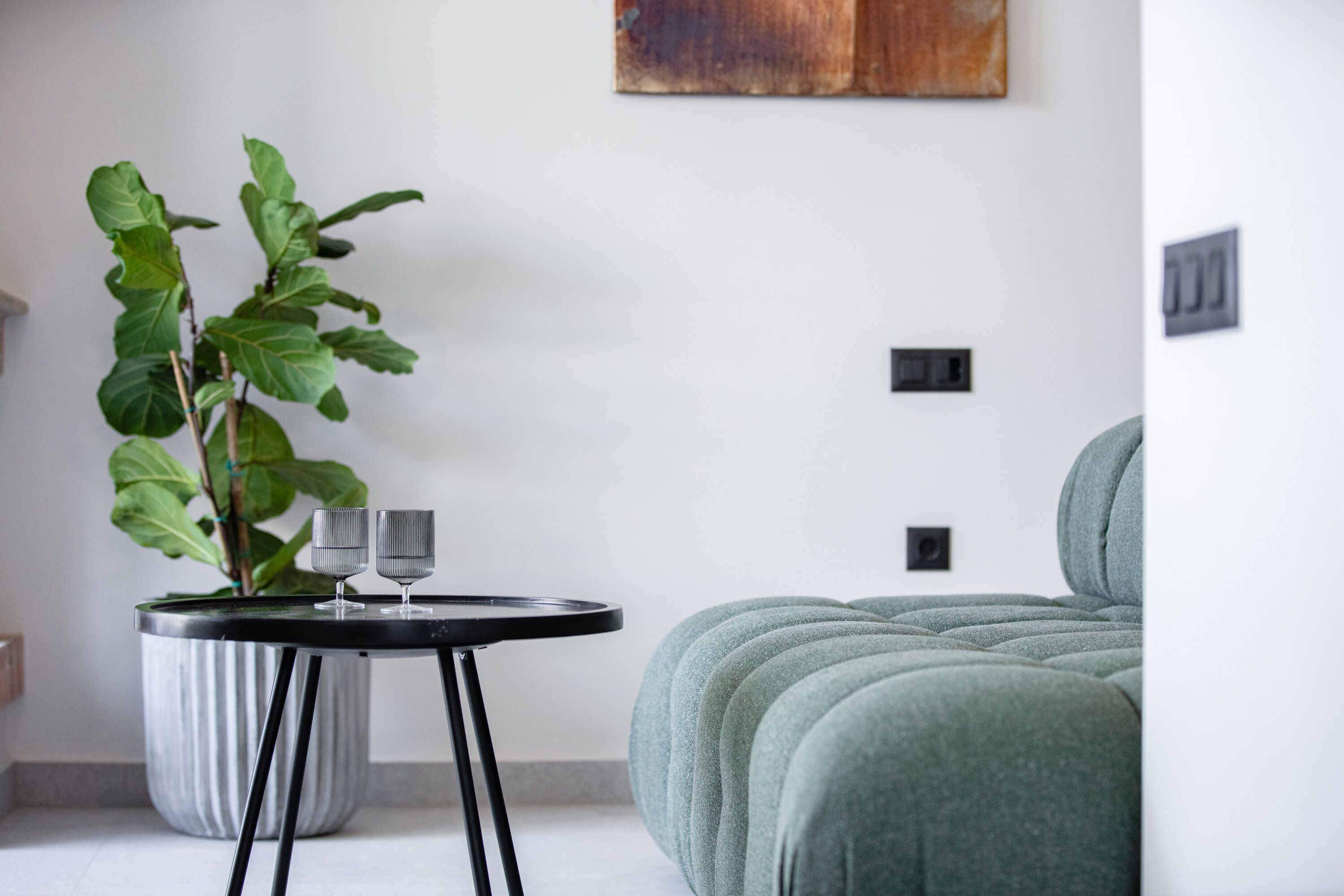 A modern living space with a round table, two glasses, and a potted plant.