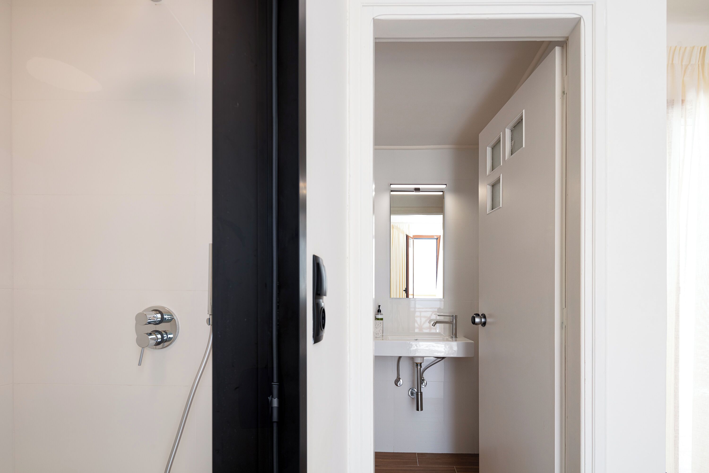 A bathroom with a white sink, a mirror, and a shower.