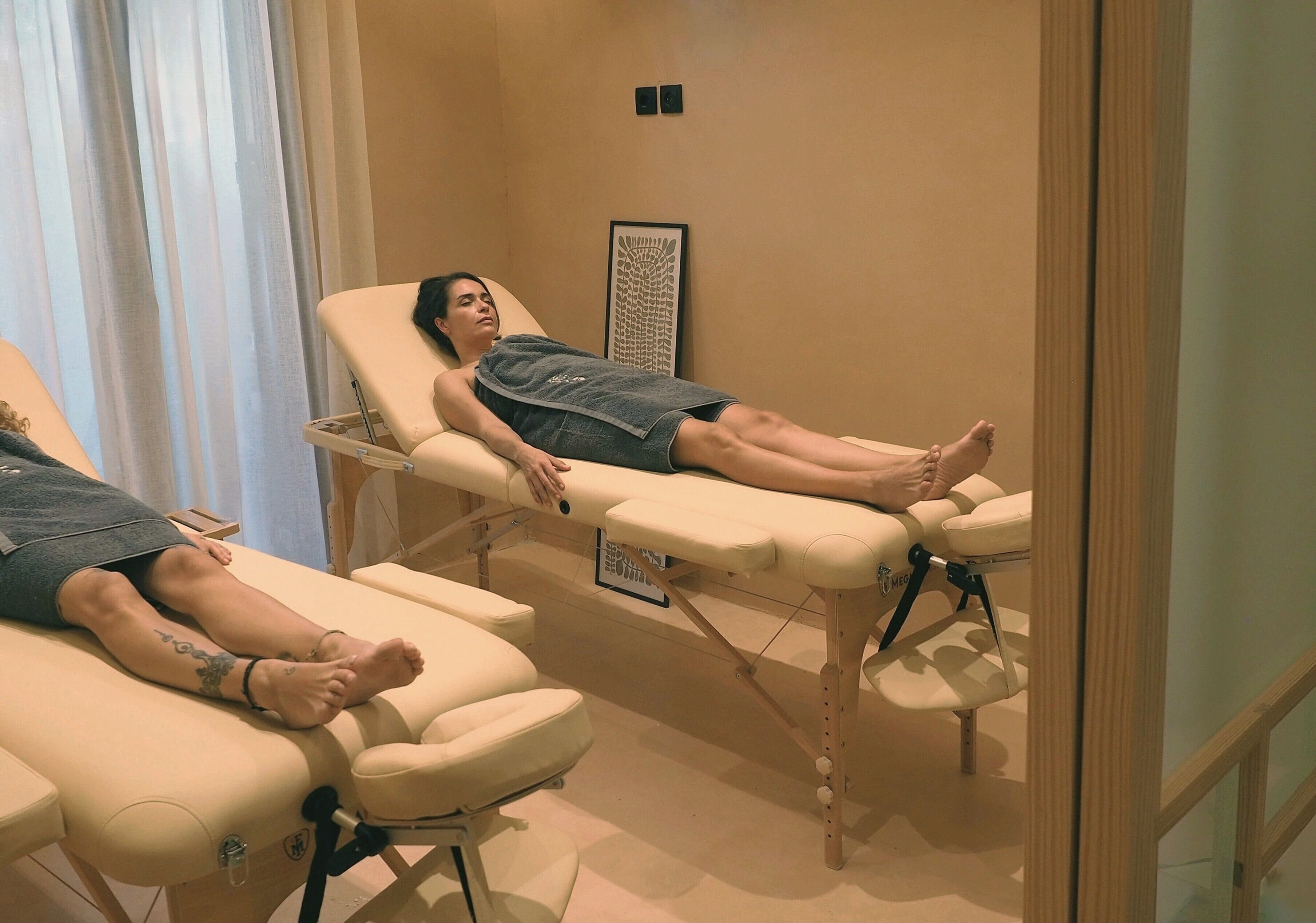 A room with two reclining massage chairs, a framed artwork on the wall, and a wooden floor.