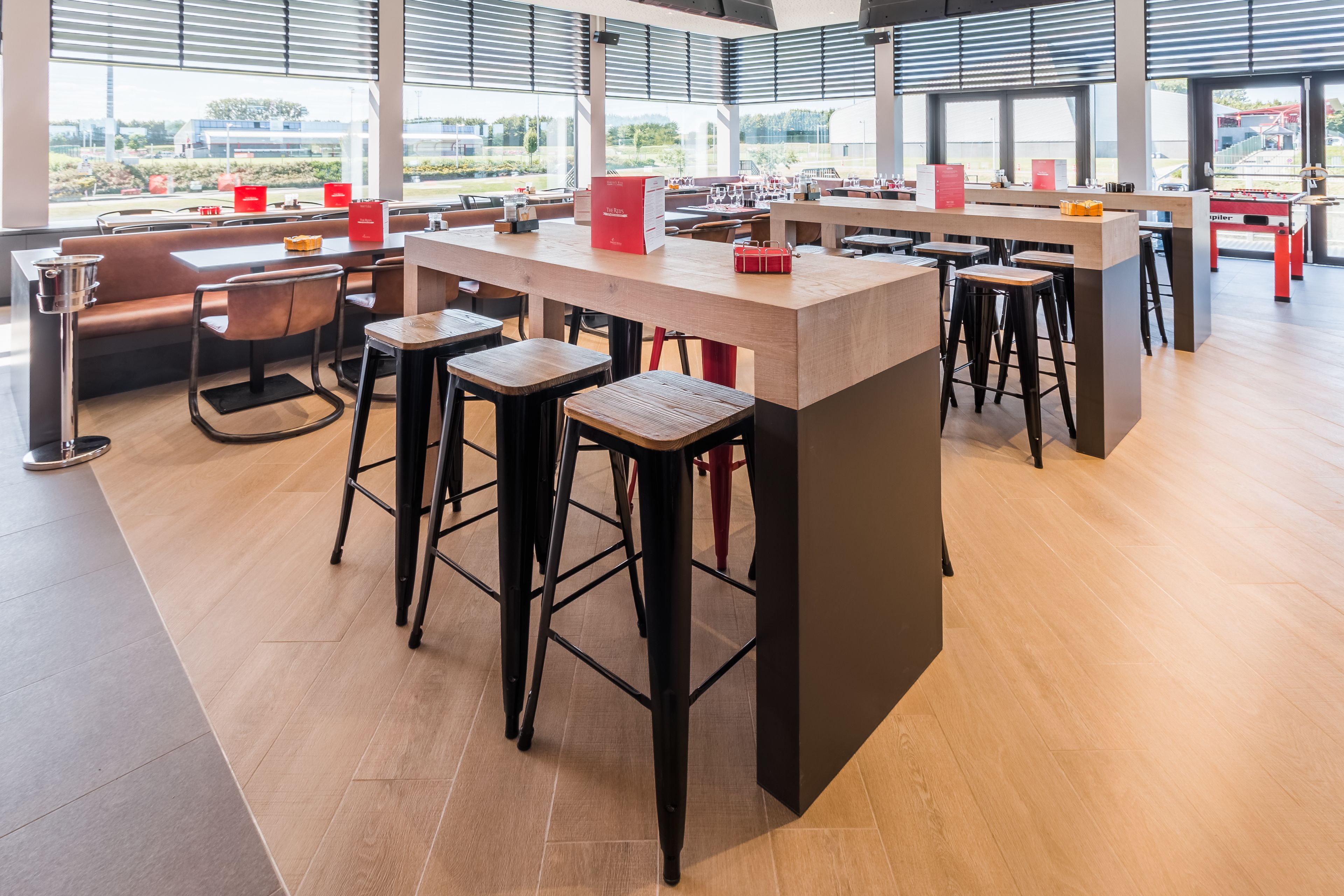 A modern restaurant with a central bar area, high tables, and stools.