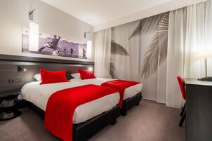 Une chambre d’hôtel avec deux lits, un bureau et un grand tableau encadré au mur.