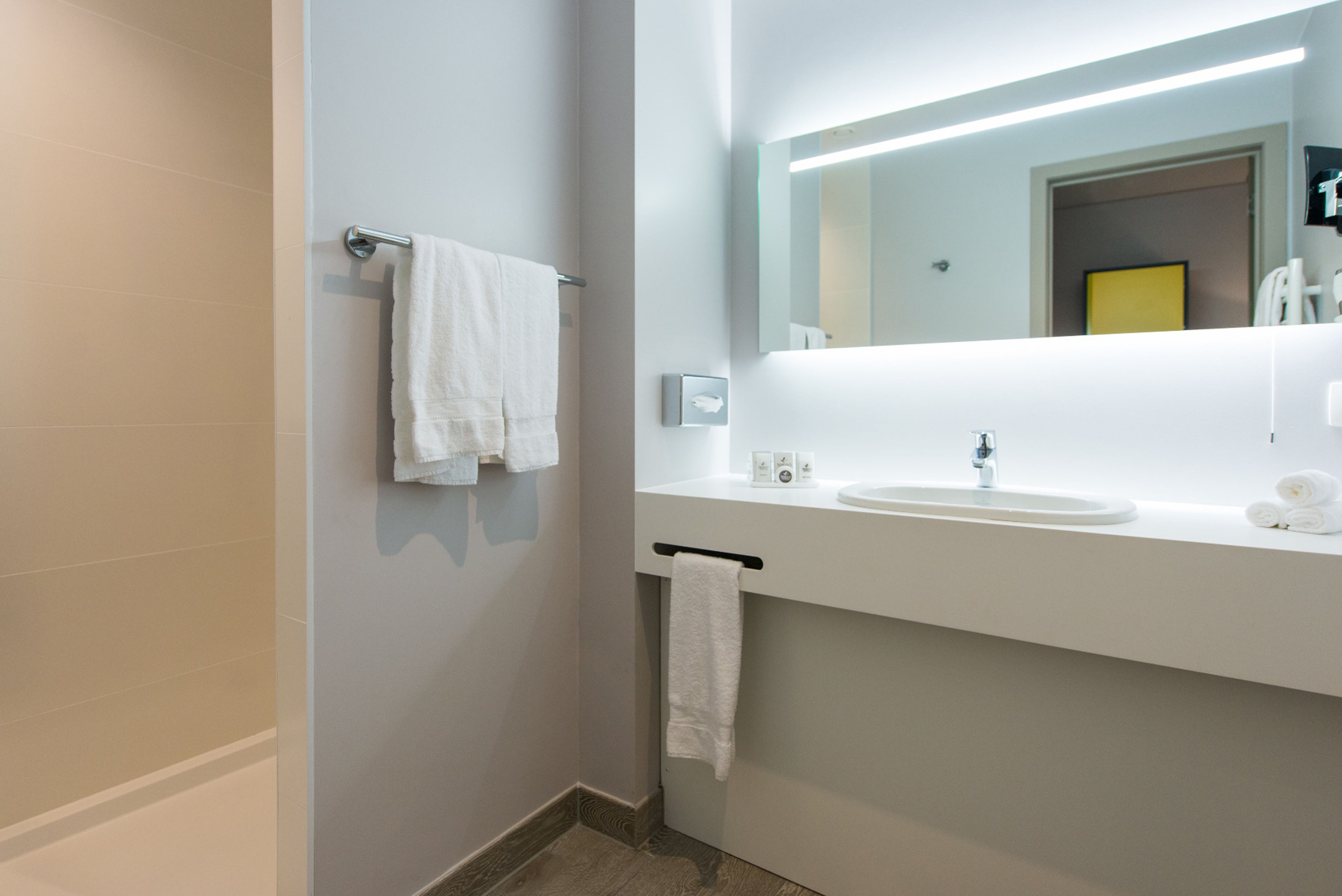 A modern bathroom with a white sink, mirror, and towel rack.