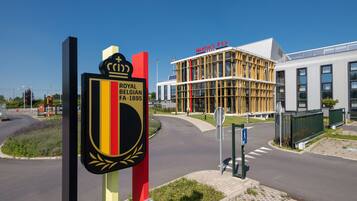 Un bâtiment moderne dont la façade porte une enseigne indiquant « Royal Belgian FA 1895 » et « Martin's Red ».