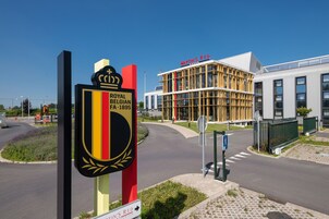 Un bâtiment moderne dont la façade porte une enseigne indiquant « Royal Belgian FA 1895 » et « Martin's Red ».