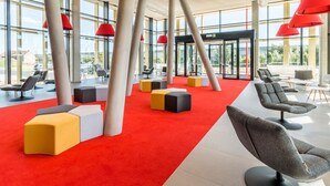 A modern lobby with red carpet, multiple seating areas, and large windows. - Martin's Red (Tubize)