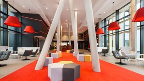 A modern lobby with high ceilings, red pendant lighting, and a red carpet. - Martin's Red (Tubize)