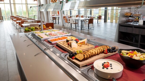 A buffet with various food items and a seating area with tables and chairs. - Martin's Red (Tubize)