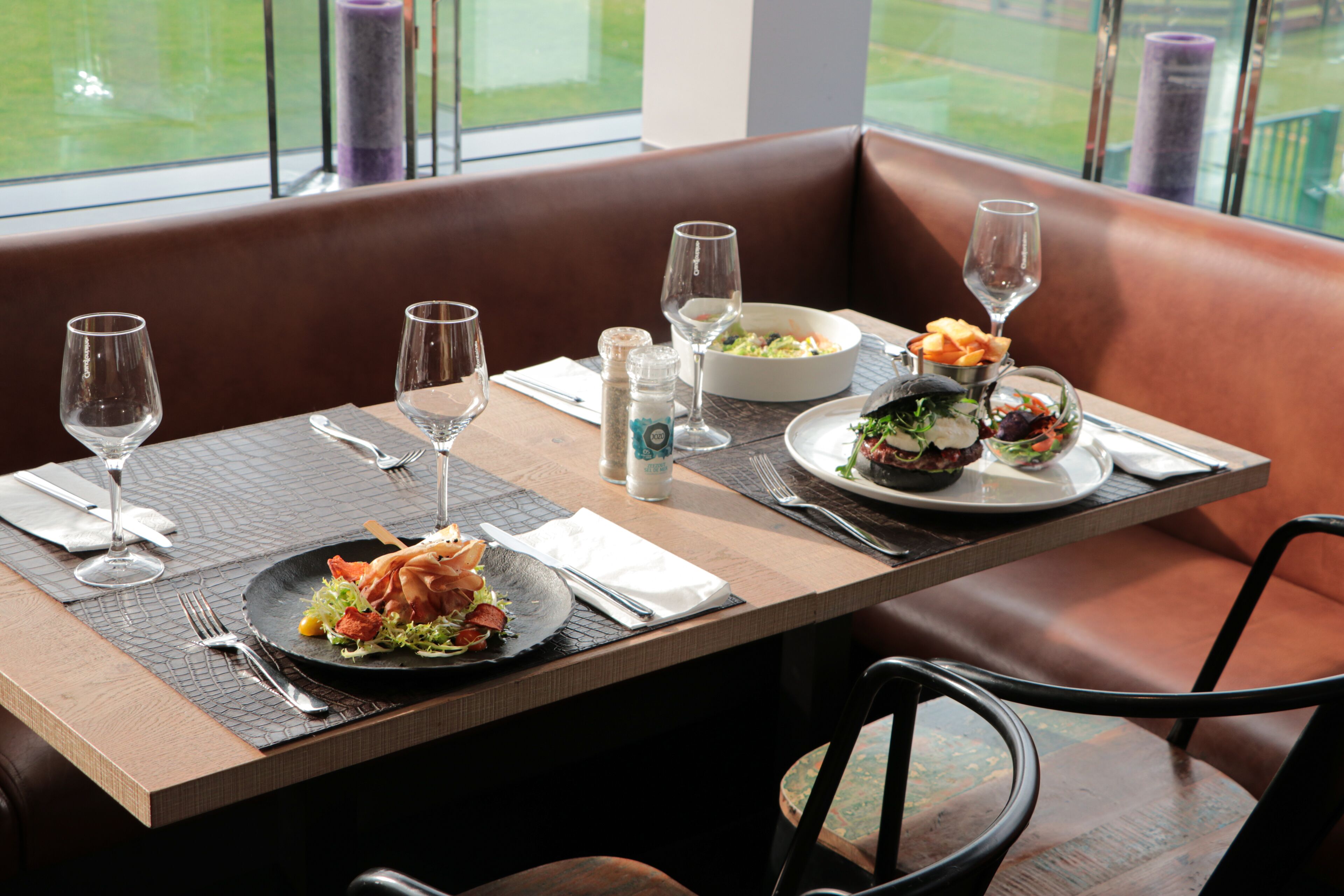 A restaurant table with plates of food, wine glasses, and cutlery.