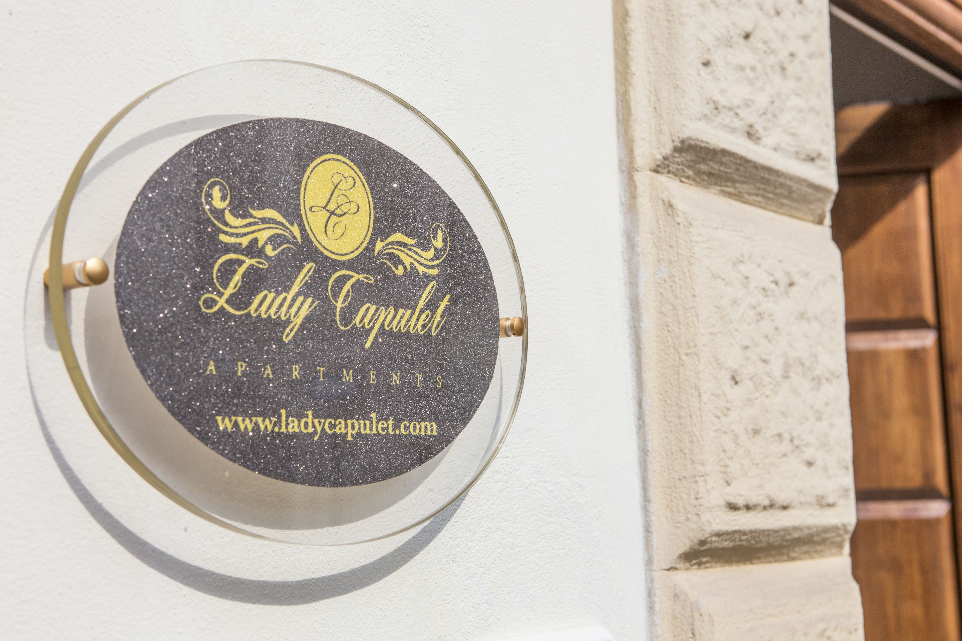 Un segnale circolare con il testo 'Lady Capulet Apartments' e un indirizzo web.