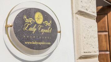 Un segnale circolare con il testo 'Lady Capulet Apartments' e un indirizzo web.