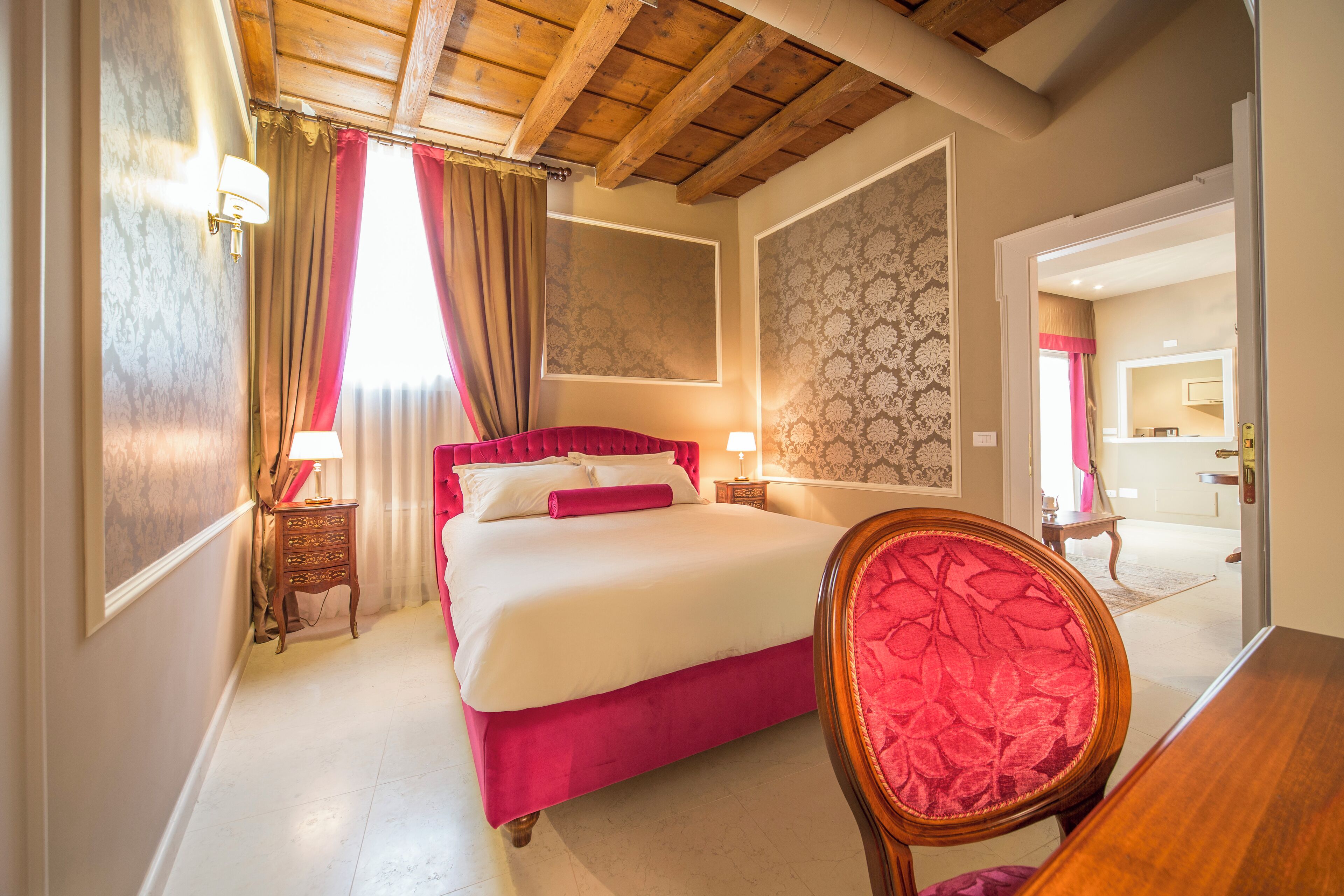 Una camera da letto con un letto grande, una testiera in legno, una sedia rossa e un tavolino.